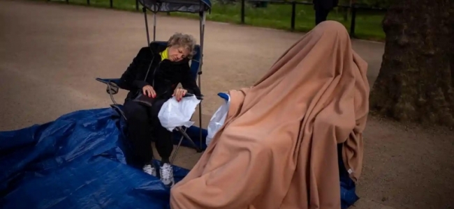 Doi suporteri ai monarhiei britanice se odihnesc pe traseul ce va fi urmat de regele Charles în ziua încoronări